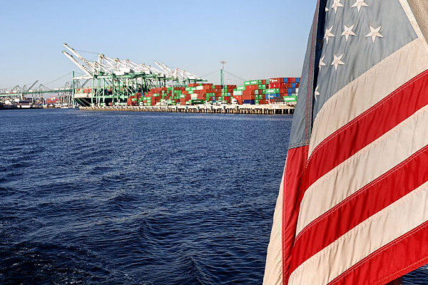American flag with shipping port in background